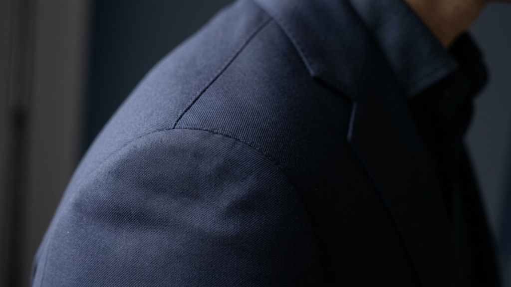 "Close-up of suit jacket shoulder seam showing perfect alignment at the shoulder bone for correct 3 piece suit fit